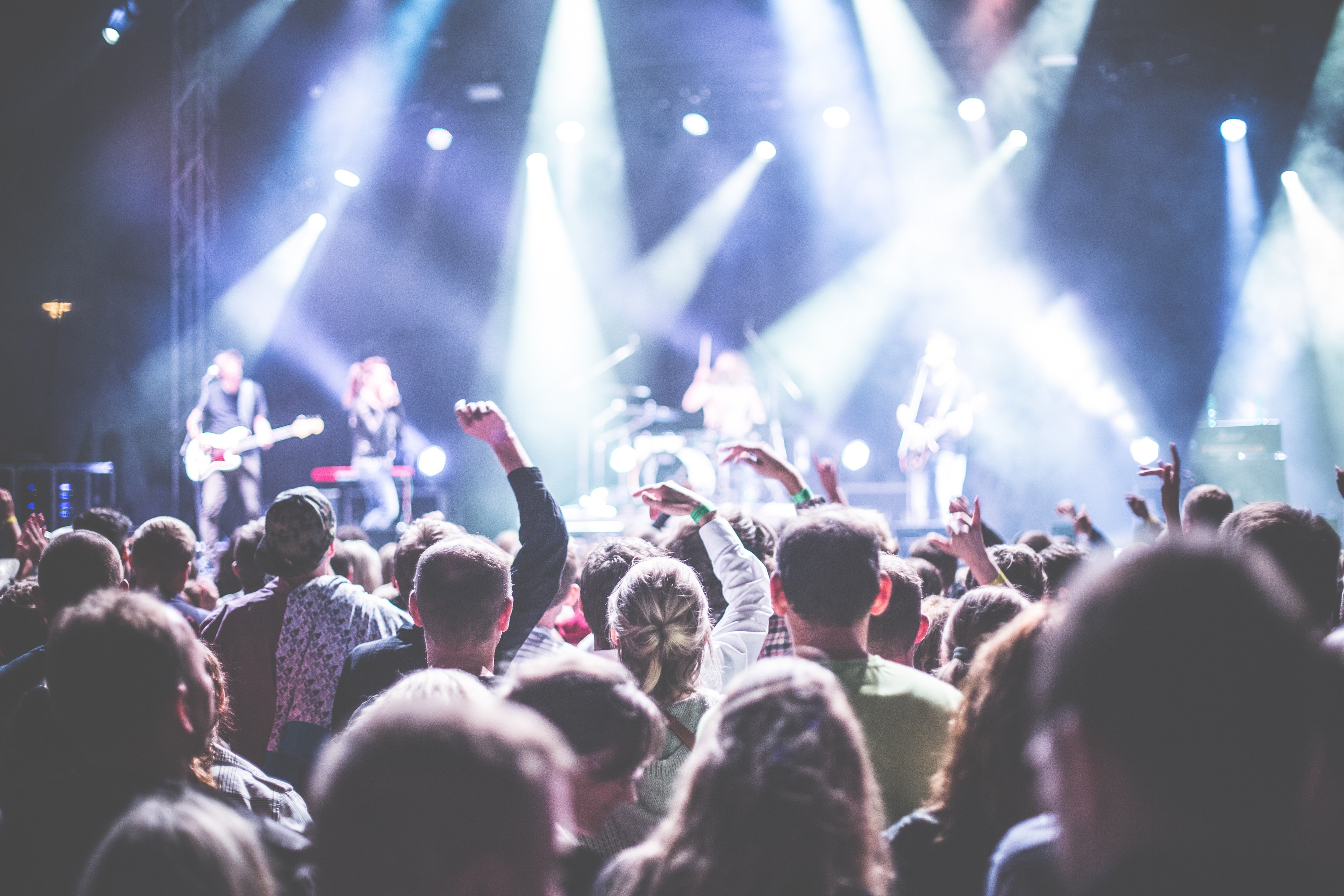 Large festival crowd watching a live concert with bright stage lights