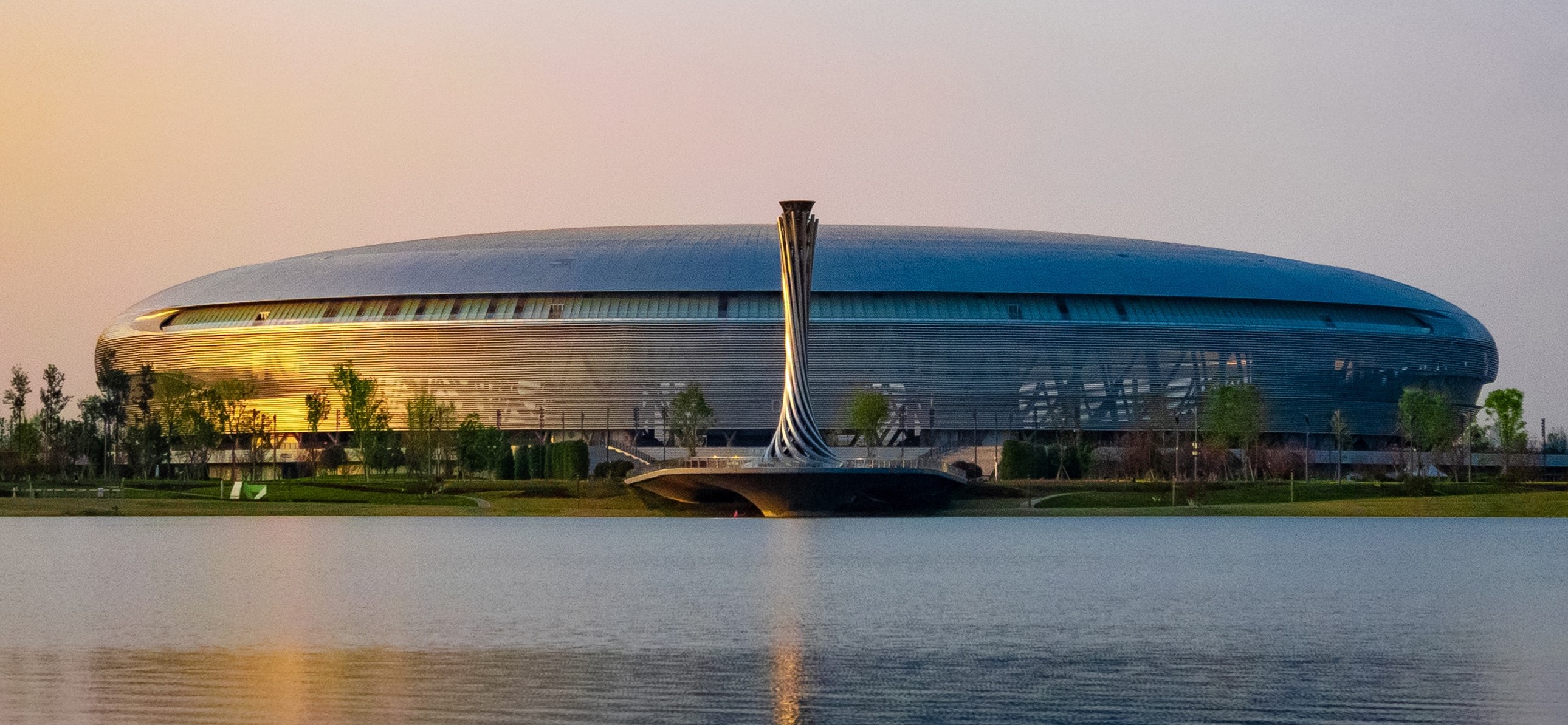 Modern stadium exterior beside water at dusk for high-volume concession service