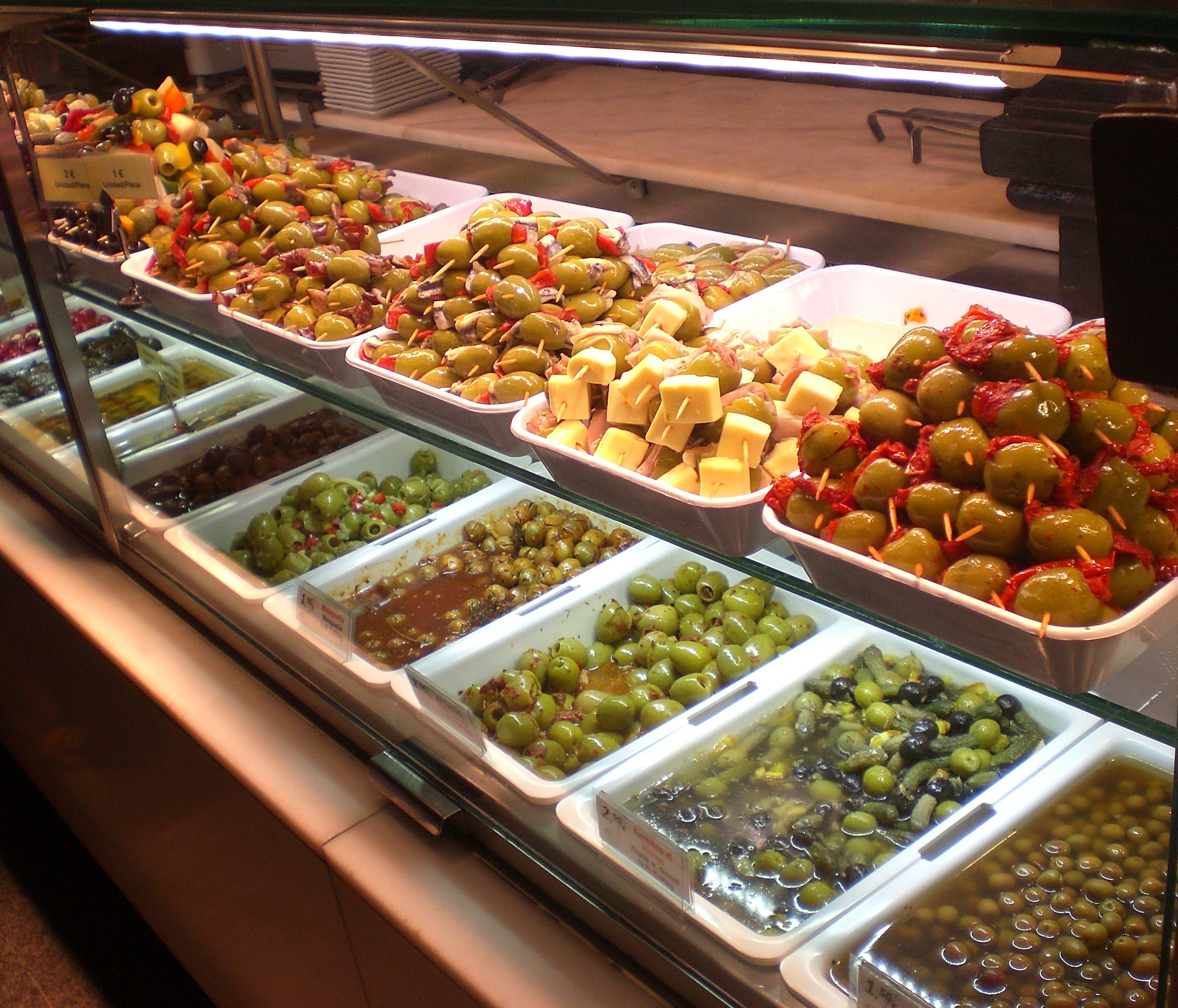 Prepared antipasti trays displayed behind glass at a walk-up food service counter